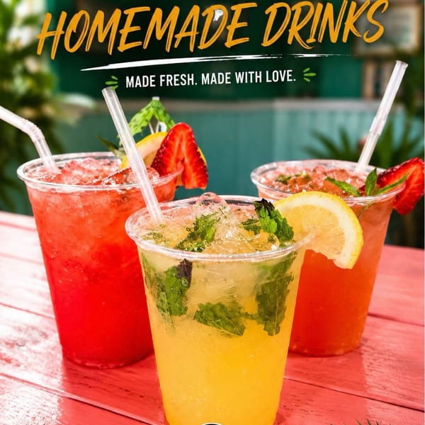 Three vibrant homemade drinks, including a mojito and two fruit-based beverages, on a red wooden table.